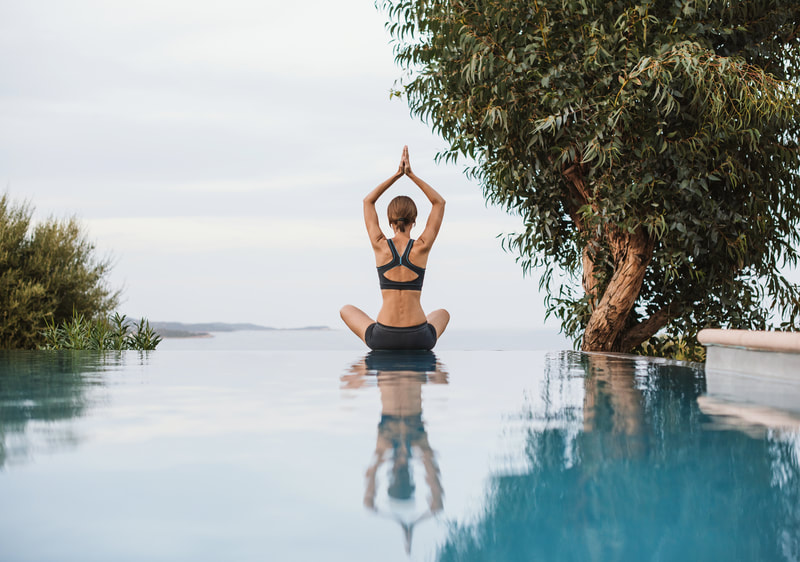 Woman doing yoga at the edge of an infinity pool